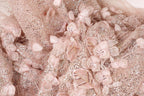 The image is a close-up of a delicate, intricately designed fabric with a floral pattern. The fabric is adorned with numerous small, pink flowers and sequins, creating a visually appealing and detailed appearance.