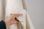 A hand holding a piece of fabric with a striped pattern.
