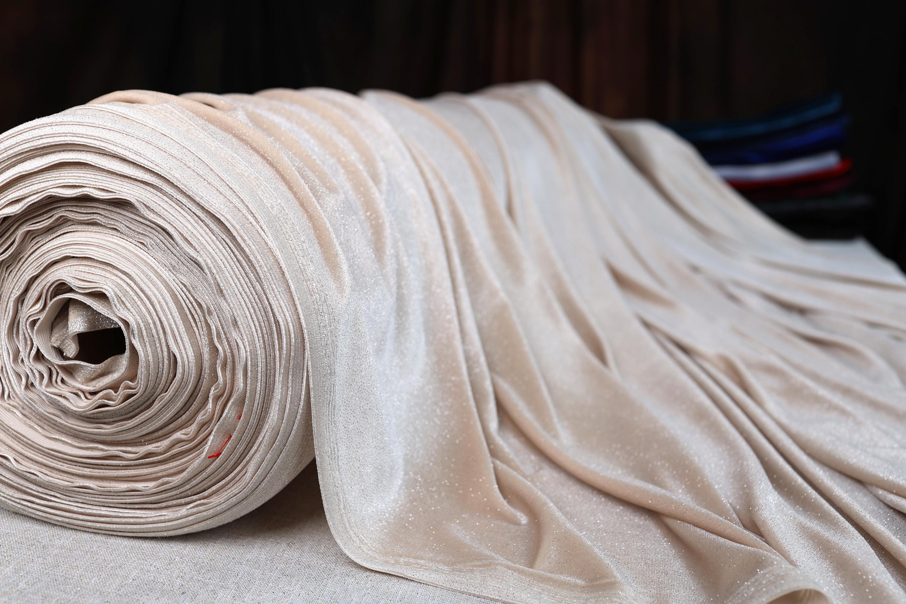 a roll of white fabric sitting on top of a bed