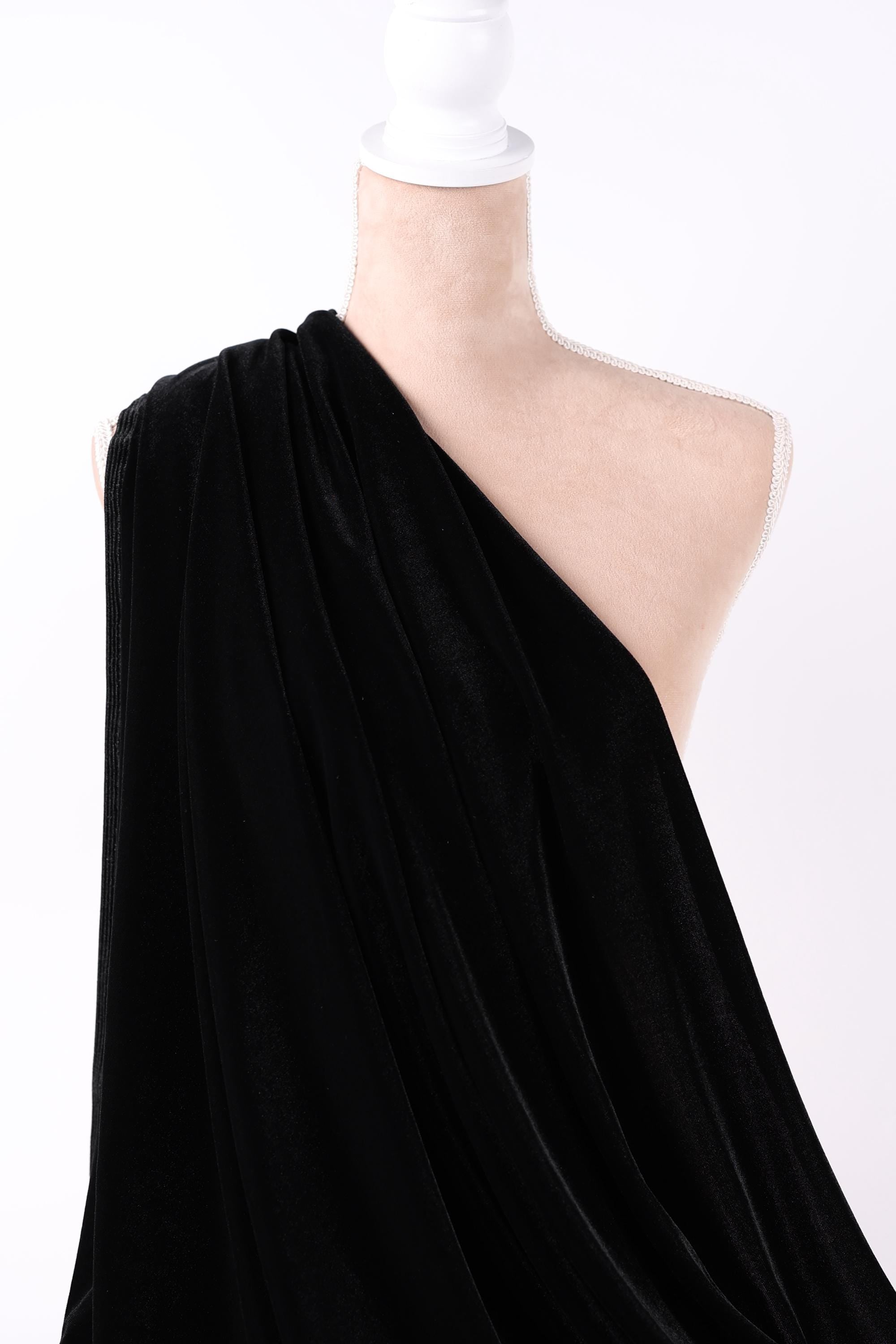 A close-up view of a black fabric draped over a white surface, with a white object partially visible in the frame.