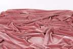 A close-up view of a crumpled, pink velvet fabric.