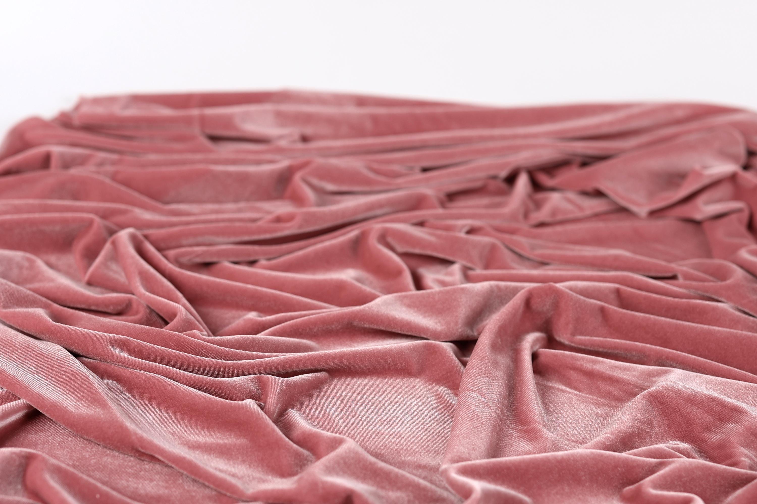 A close-up view of a crumpled, pink velvet fabric.