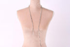 A mannequin wearing a necklace with a long, silver chain.