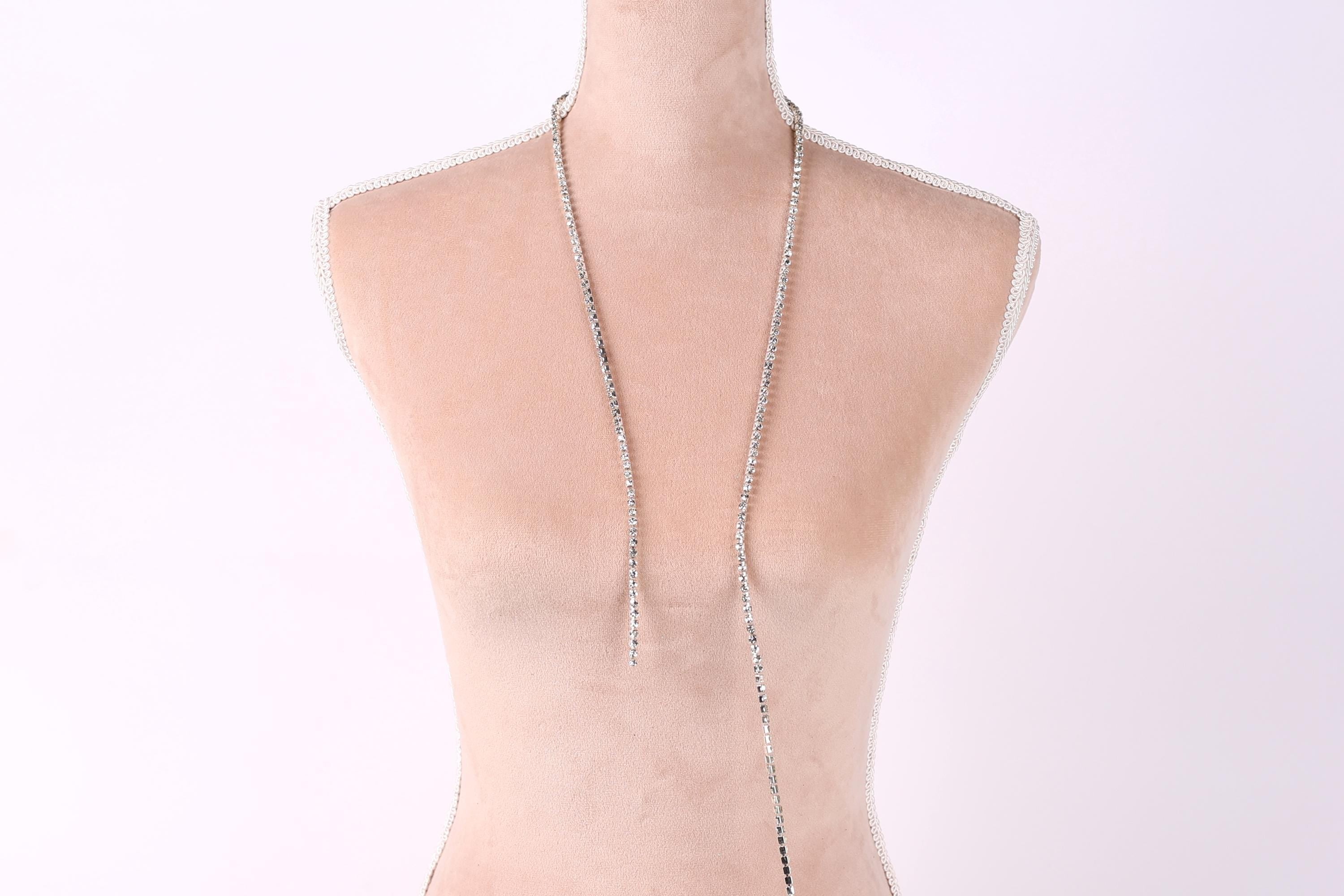 A mannequin wearing a necklace with a long, silver chain.