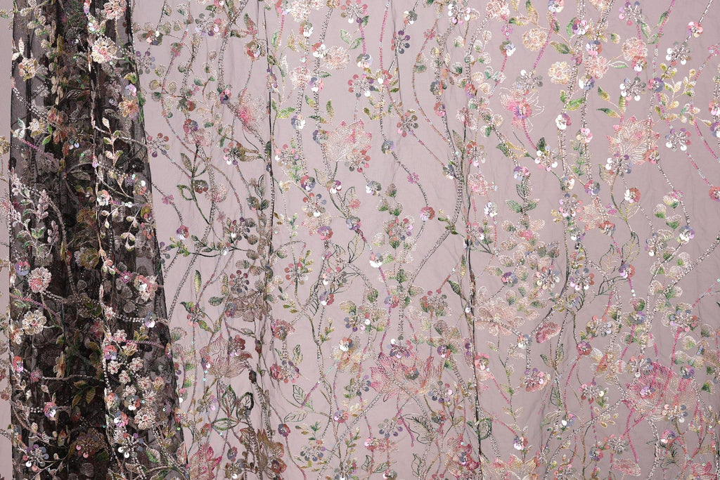 a close-up view of a fabric with a floral pattern, including pink, green, and white flowers and leaves. The fabric appears to be a sheer material, with a dark background that contrasts with the lighter colors of the floral design.