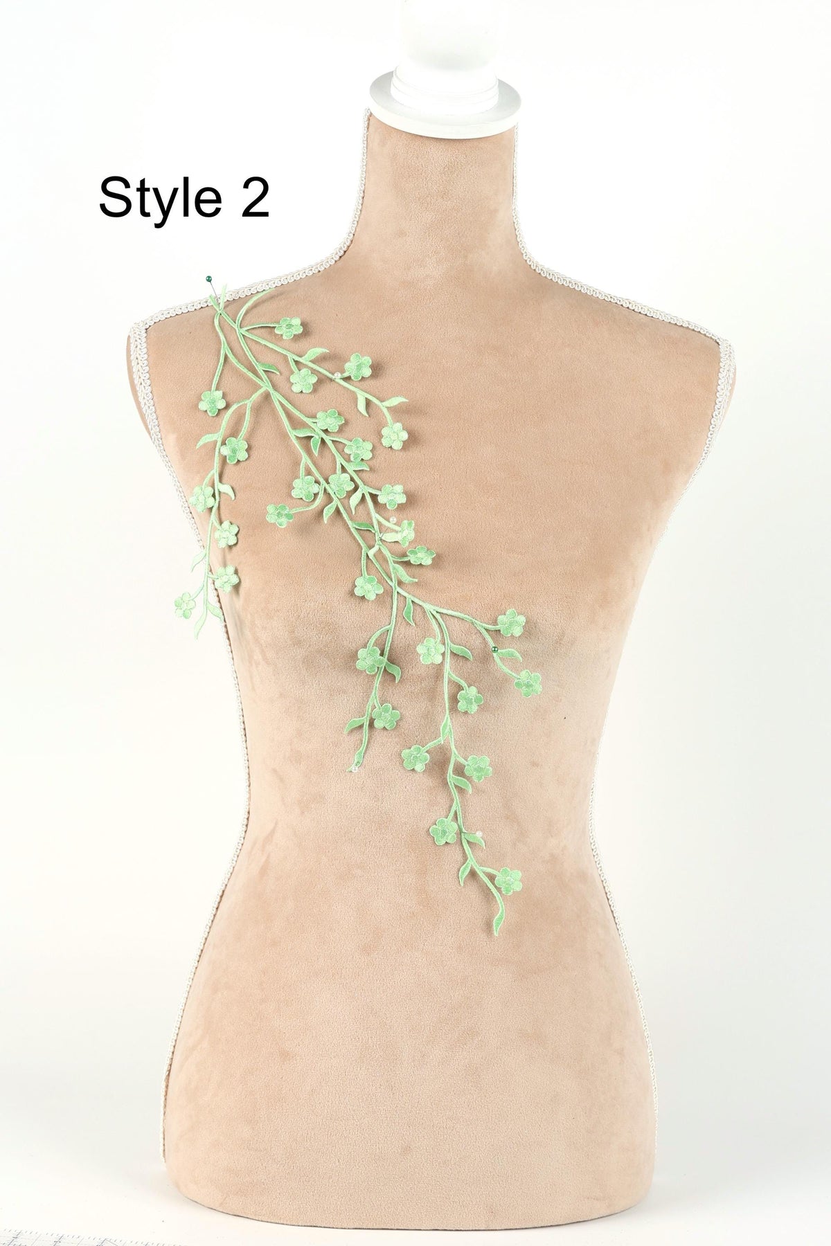 A mannequin with a green branch-like decoration on its shoulder.