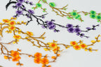 a close-up view of a variety of colorful floral designs, including yellow and orange flowers, purple flowers, and green flowers, arranged in a visually appealing manner.