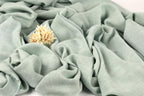a close-up view of a light green fabric with a small yellow flower resting on it.