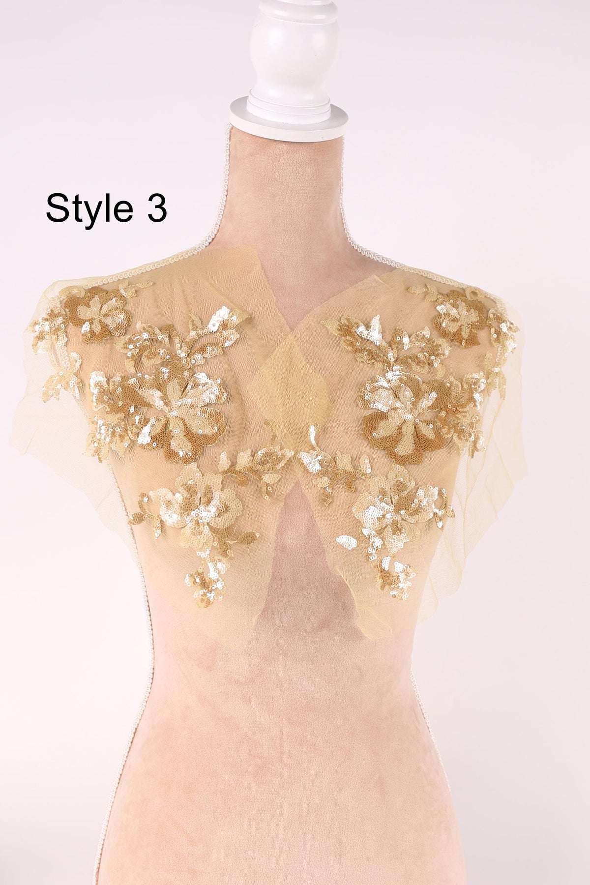 A mannequin wearing a gold and beige sequined jacket with a floral pattern.