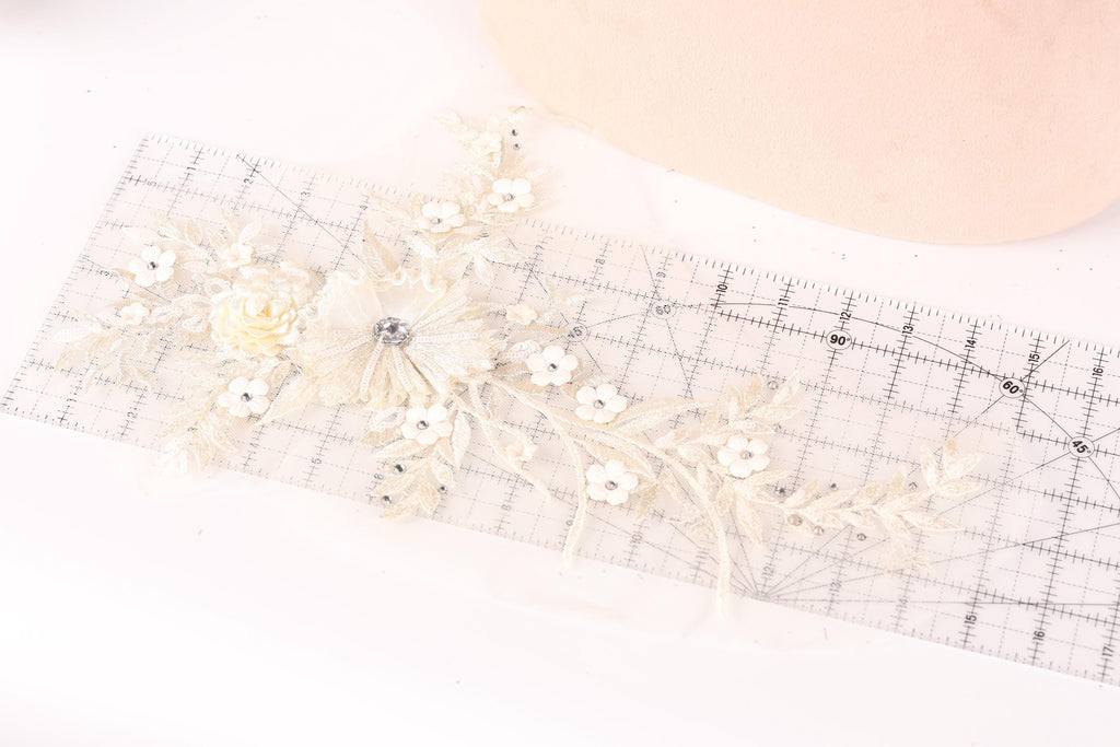 a delicate piece of lace with a flower design, placed on a ruler for scale.