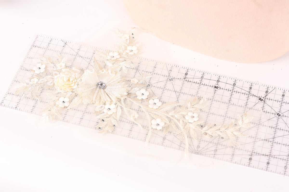 a delicate piece of lace with a flower design, placed on a ruler for scale.