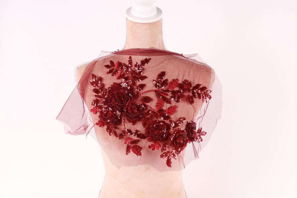 A mannequin wearing a red floral-embroidered shawl or cape.