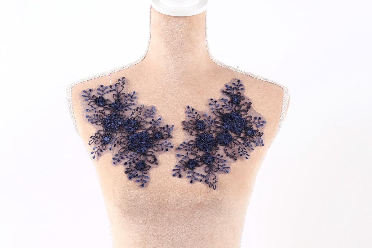 A mannequin with a beige torso wearing a black lace design on the shoulders.