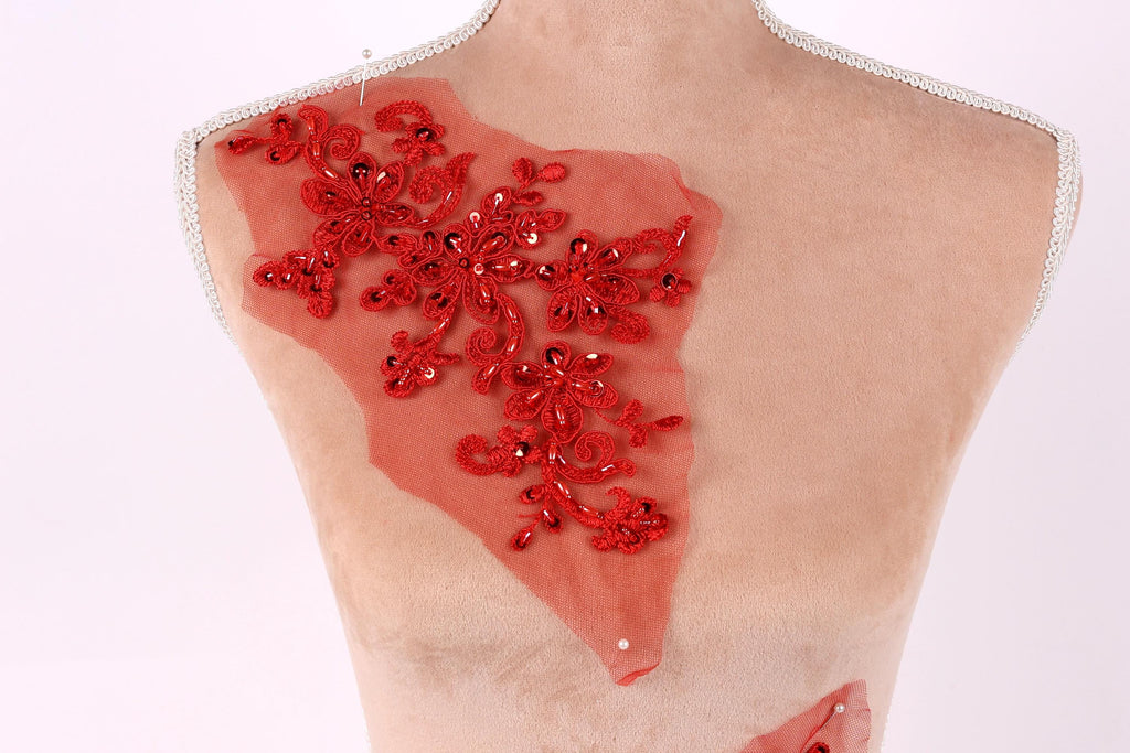 a mannequin torso with a red floral embroidered on it, set against a plain white background.