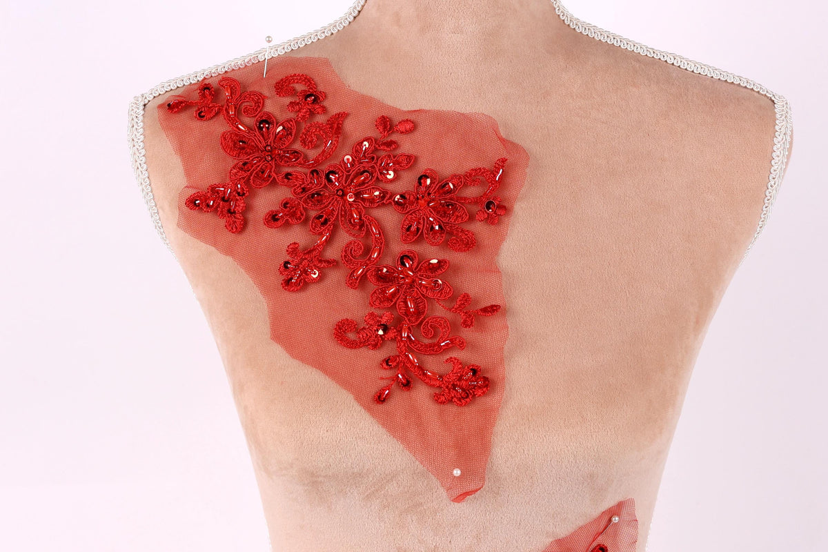 a mannequin torso with a red floral embroidered on it, set against a plain white background.