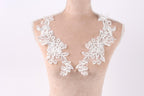 A mannequin wearing a white lace dress with intricate floral embroidery on the shoulders.