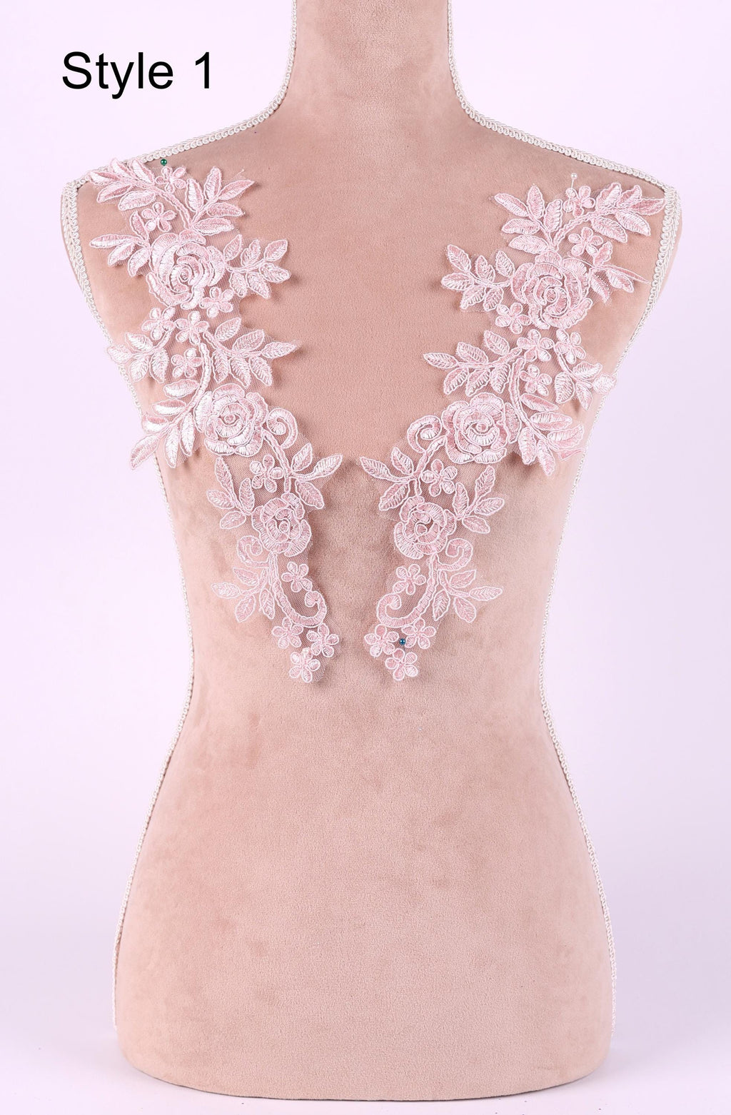 A mannequin with a pink floral lace overlay on its shoulders, displayed against a light pink background.