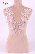 A mannequin with a pink floral lace overlay on its shoulders, displayed against a light pink background.