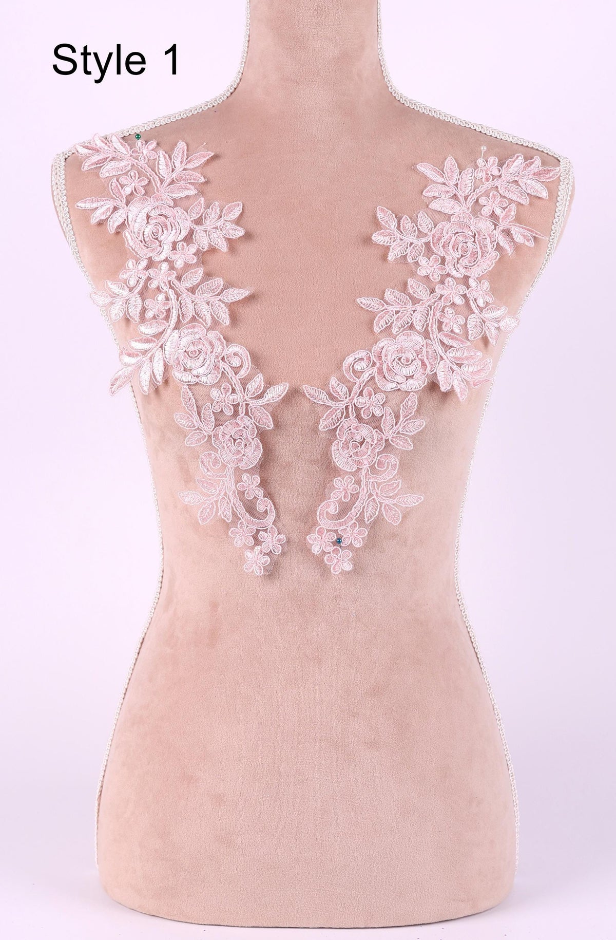 A mannequin with a pink floral lace overlay on its shoulders, displayed against a light pink background.