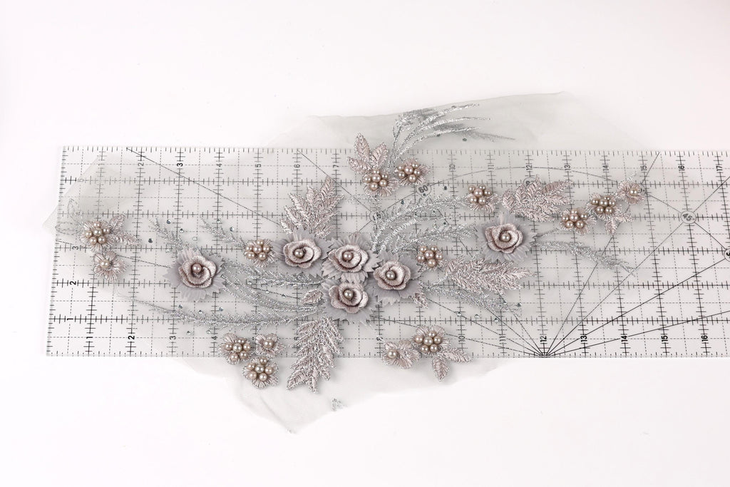 a decorative piece with a floral design, including various flowers and leaves, arranged on a transparent surface.