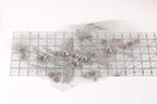 a decorative piece with a floral design, including various flowers and leaves, arranged on a transparent surface.