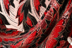 The image is a close-up of a fabric with a red and black floral pattern, featuring sequins and beads. The fabric appears to be a sheer material, with a textured and shiny appearance.