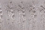 The image is a close-up of a fabric with a repeating pattern of small white and gray flowers or leaves, creating a textured and visually interesting surface.