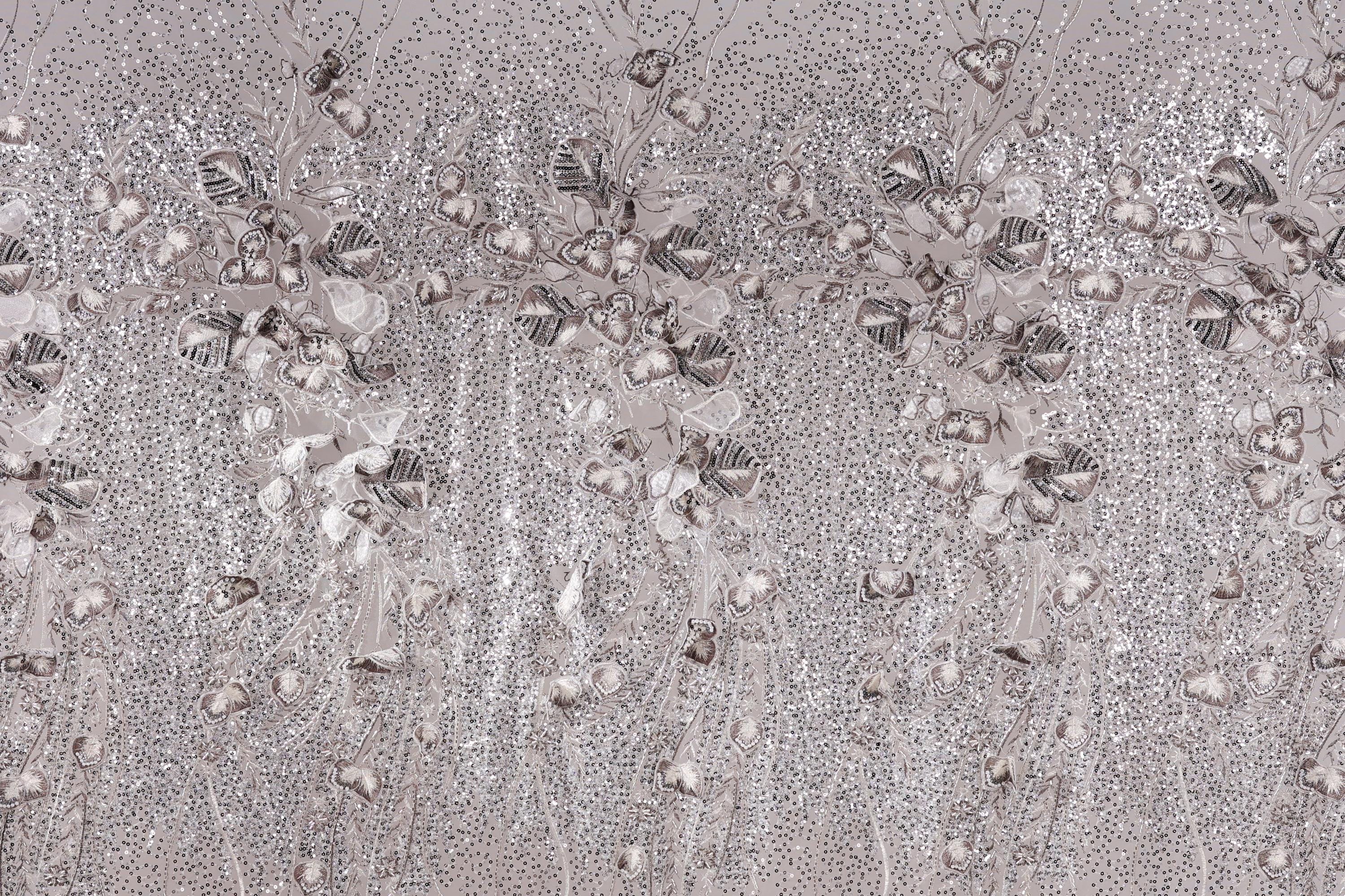 The image is a close-up of a fabric with a repeating pattern of small white and gray flowers or leaves, creating a textured and visually interesting surface.