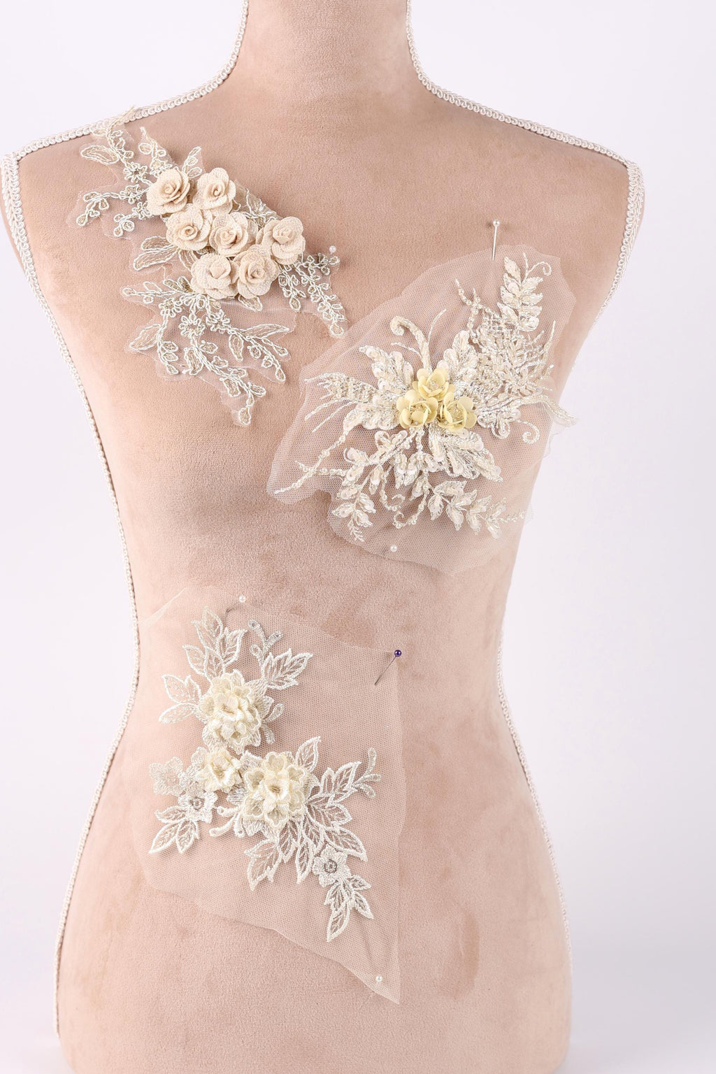 A mannequin torso with three different floral designs sewn onto it.