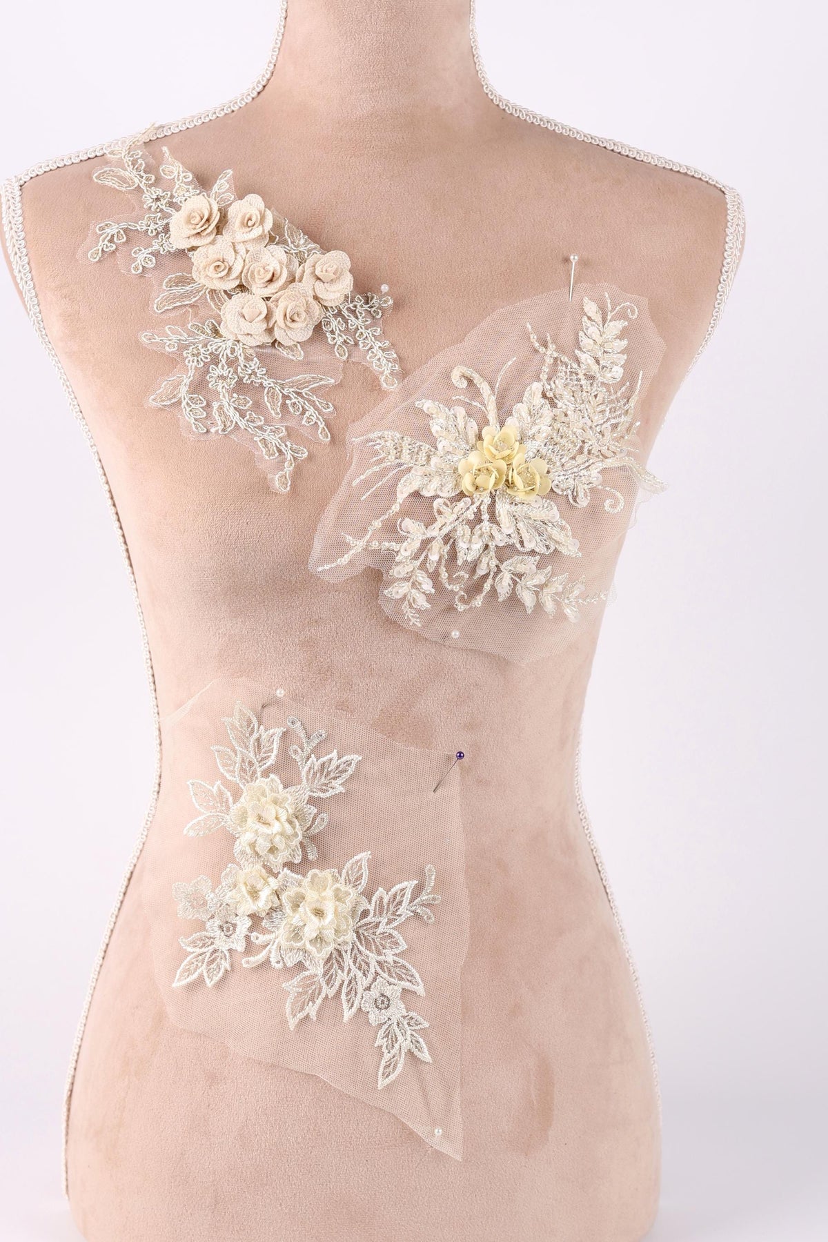 A mannequin torso with three different floral designs sewn onto it.