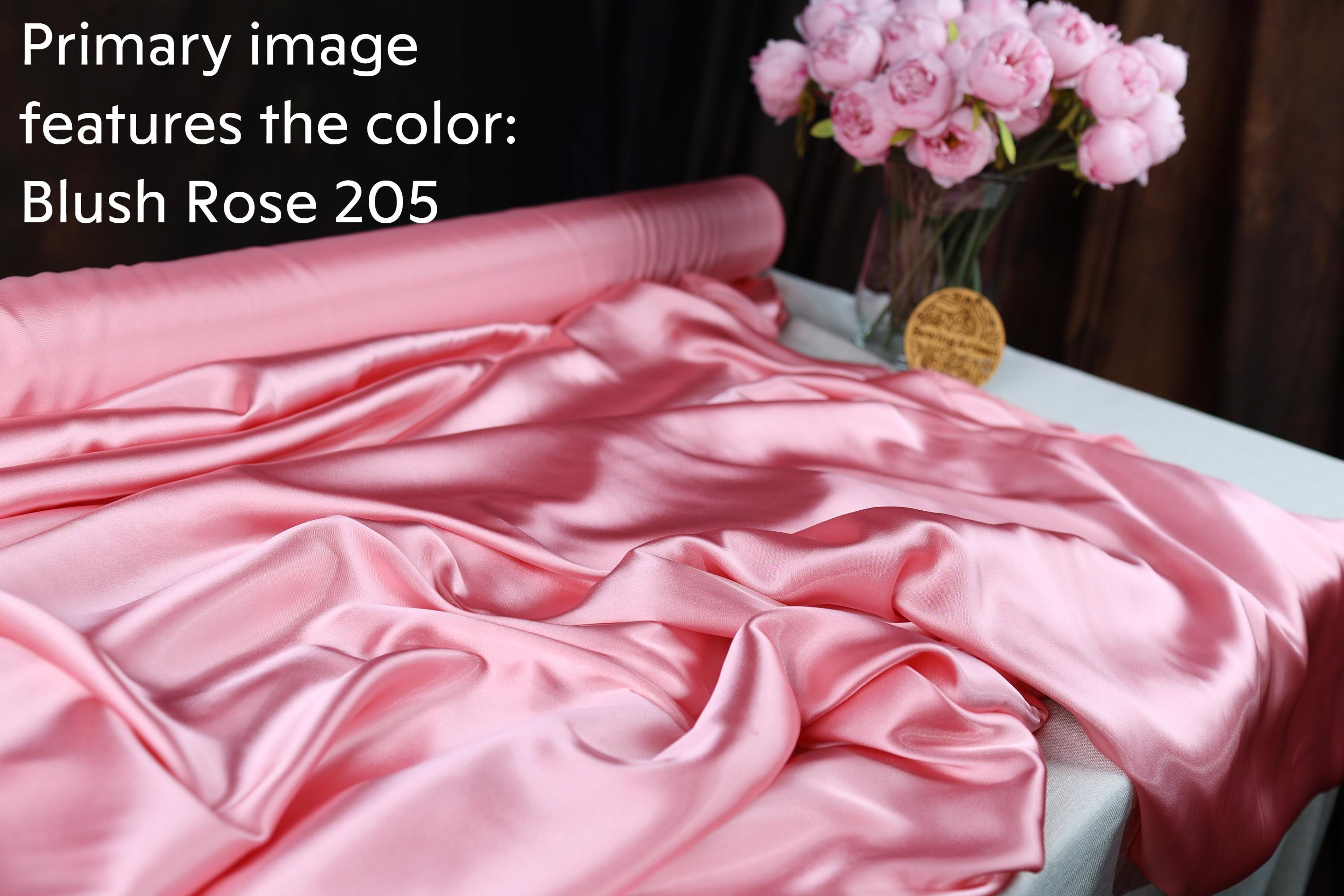 a pink satin fabric with a vase of pink flowers on a table.