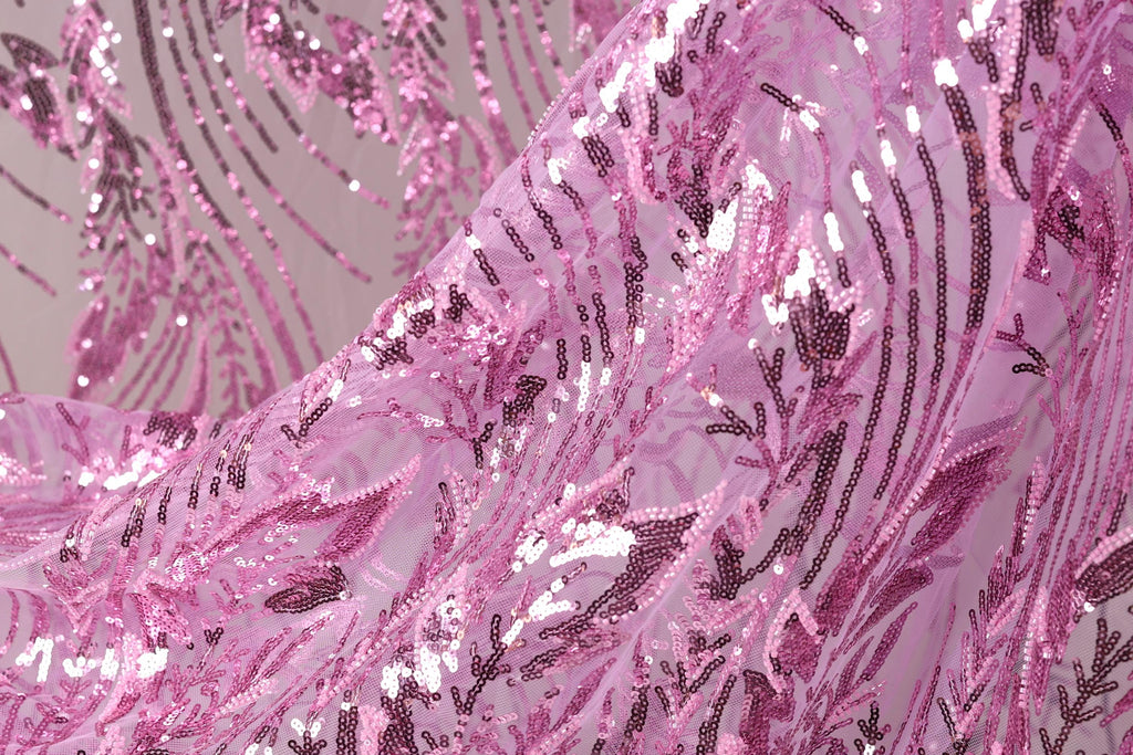 a close-up view of a fabric with a pink and purple sequin pattern. The fabric appears to be made of sheer material, with a delicate and intricate design.
