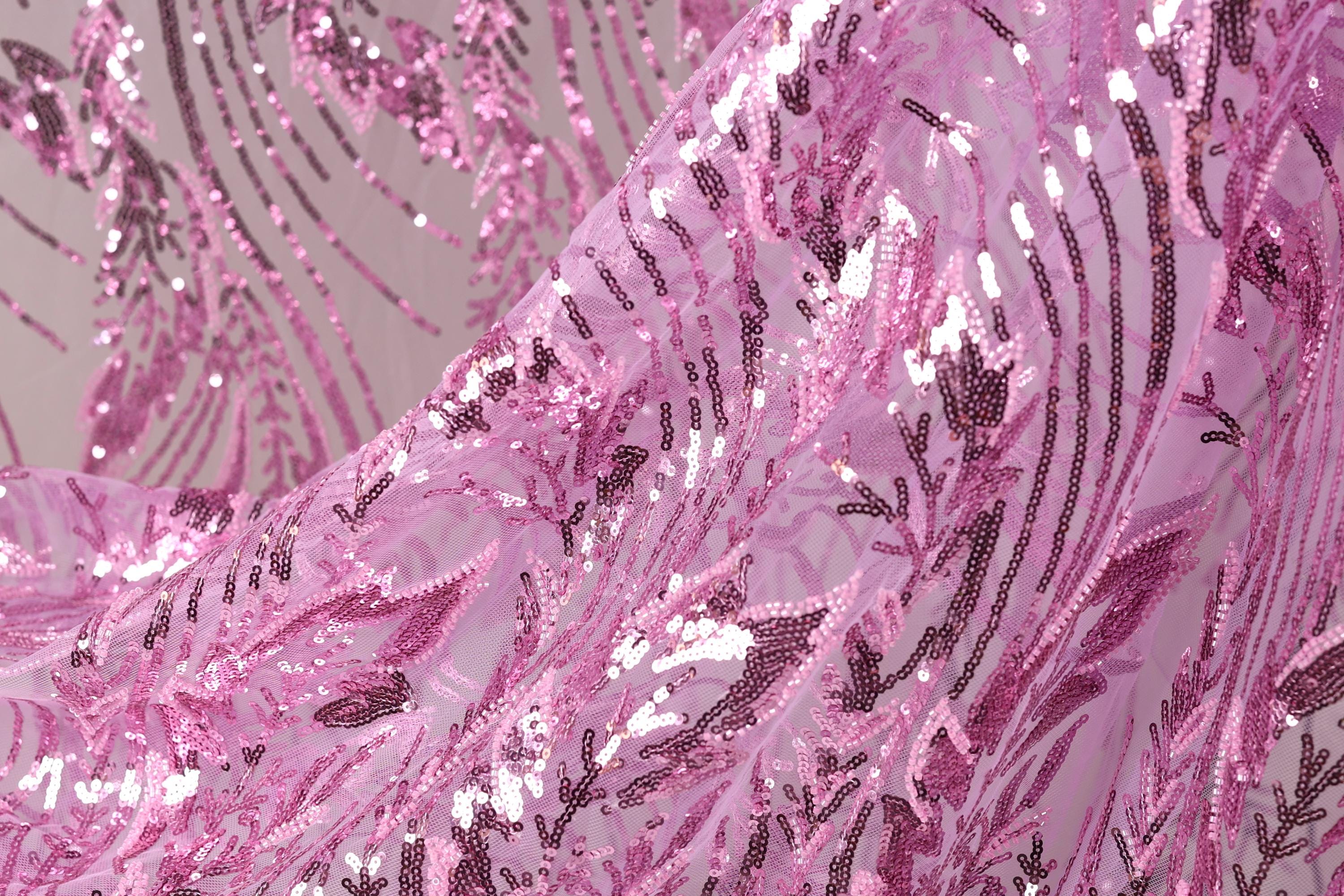 a close-up view of a fabric with a pink and purple sequin pattern. The fabric appears to be made of sheer material, with a delicate and intricate design.