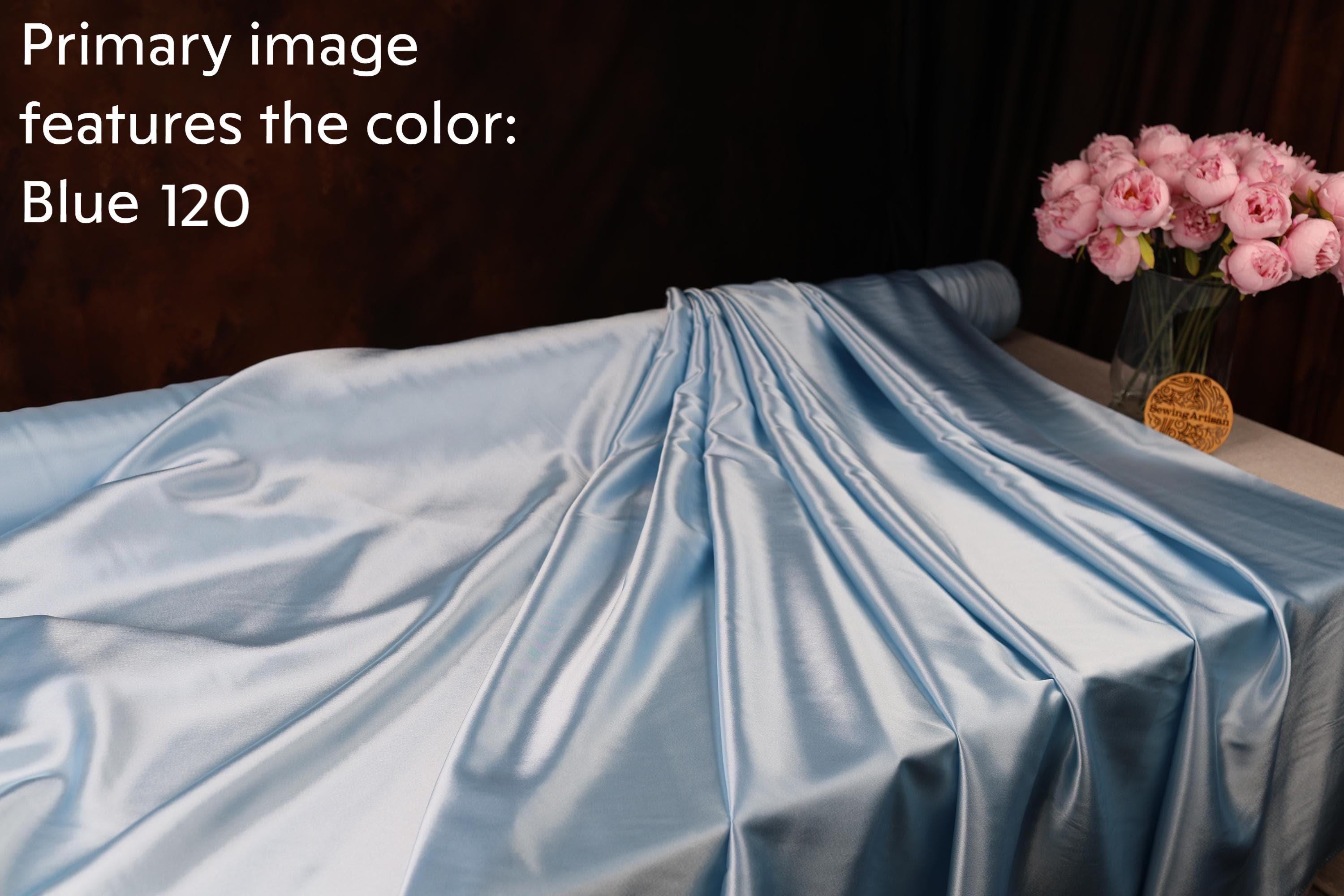 a blue fabric with a crumpled texture, and there is a vase of pink roses placed next to it.