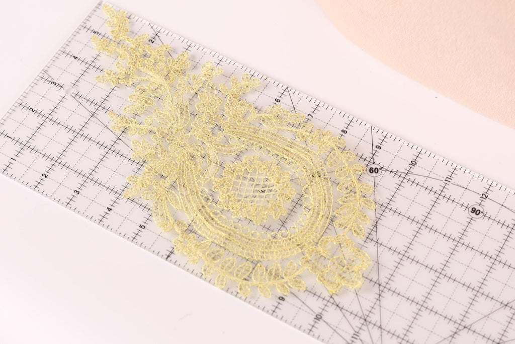 a close-up view of a clear ruler with a yellow lace pattern placed on it.