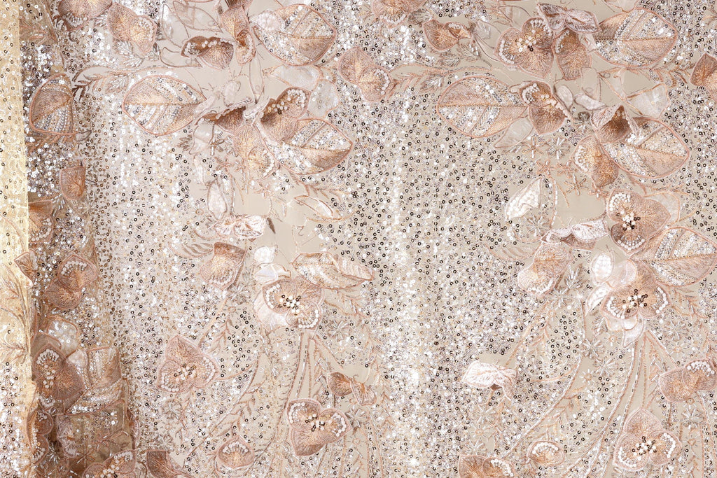 a close-up view of a fabric with a floral pattern, including leaves and flowers. The fabric appears to be made of a shiny, sequined material, giving it a sparkling and elegant appearance.