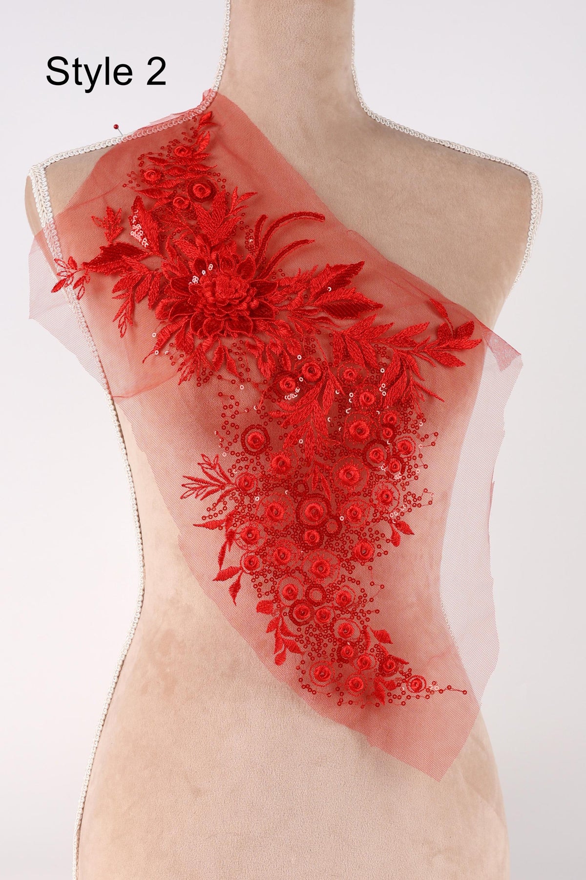 A mannequin wearing a red floral embroidered dress with a sheer overlay.
