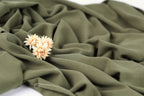 A close-up view of a green fabric with a delicate flower resting on it.