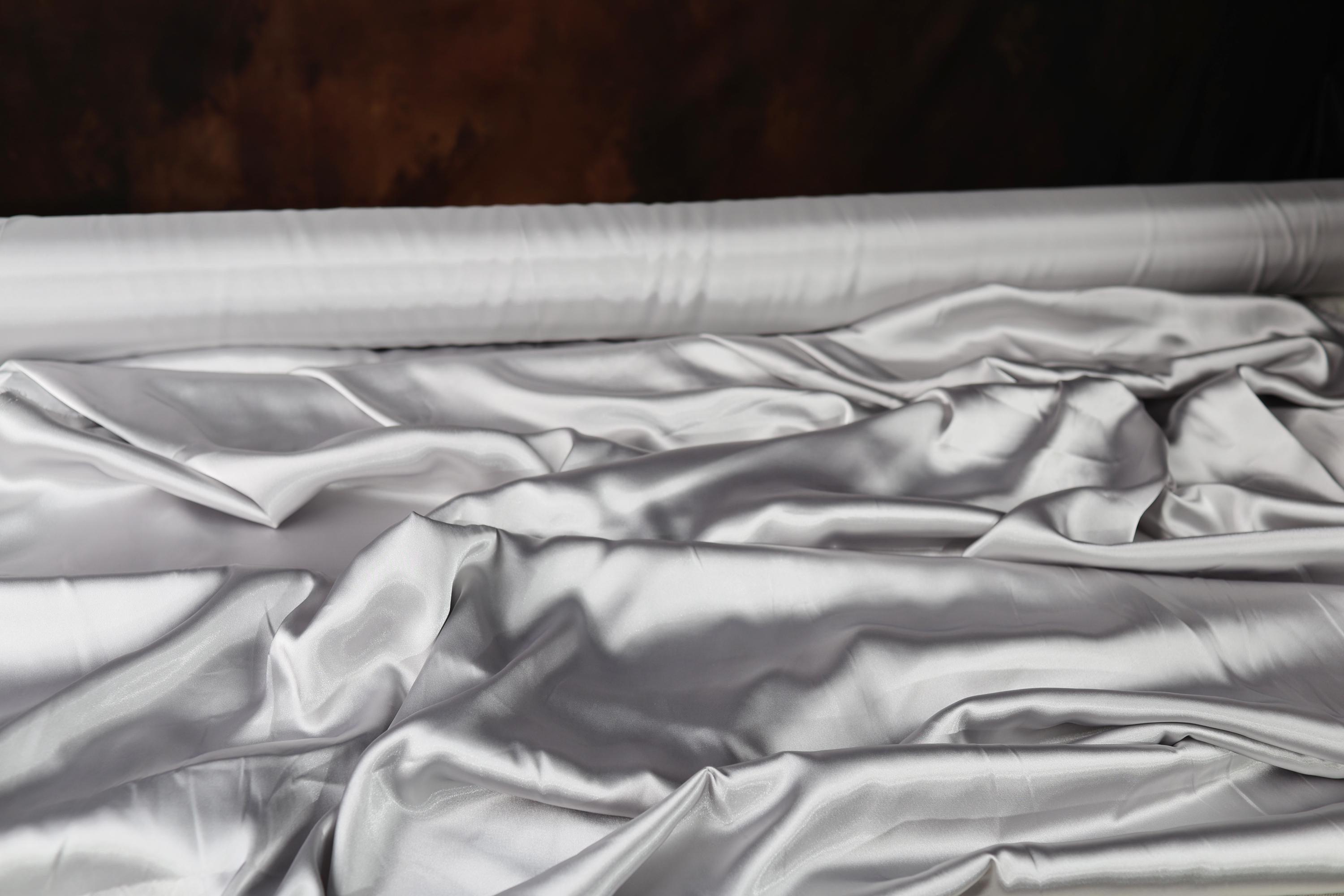 an unmade bed with white sheets and a wooden headboard