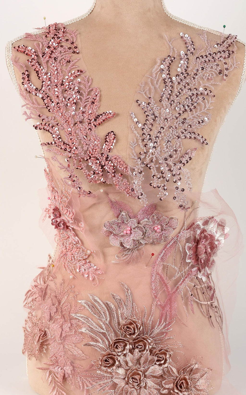 A mannequin wearing a pink and white floral dress with intricate embroidery and sequins.
