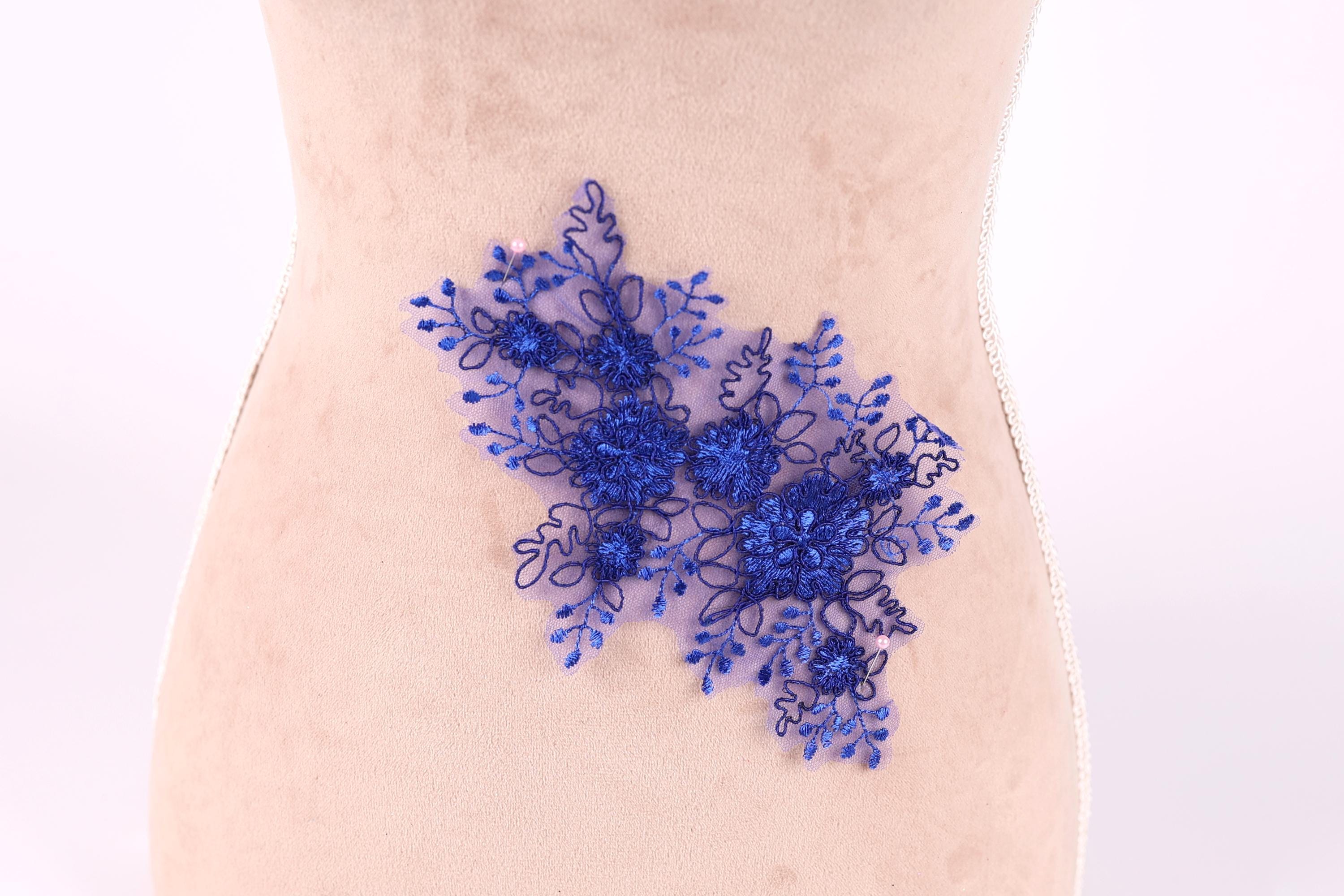 a close-up view of a fabric with a blue floral embroidered design on it.