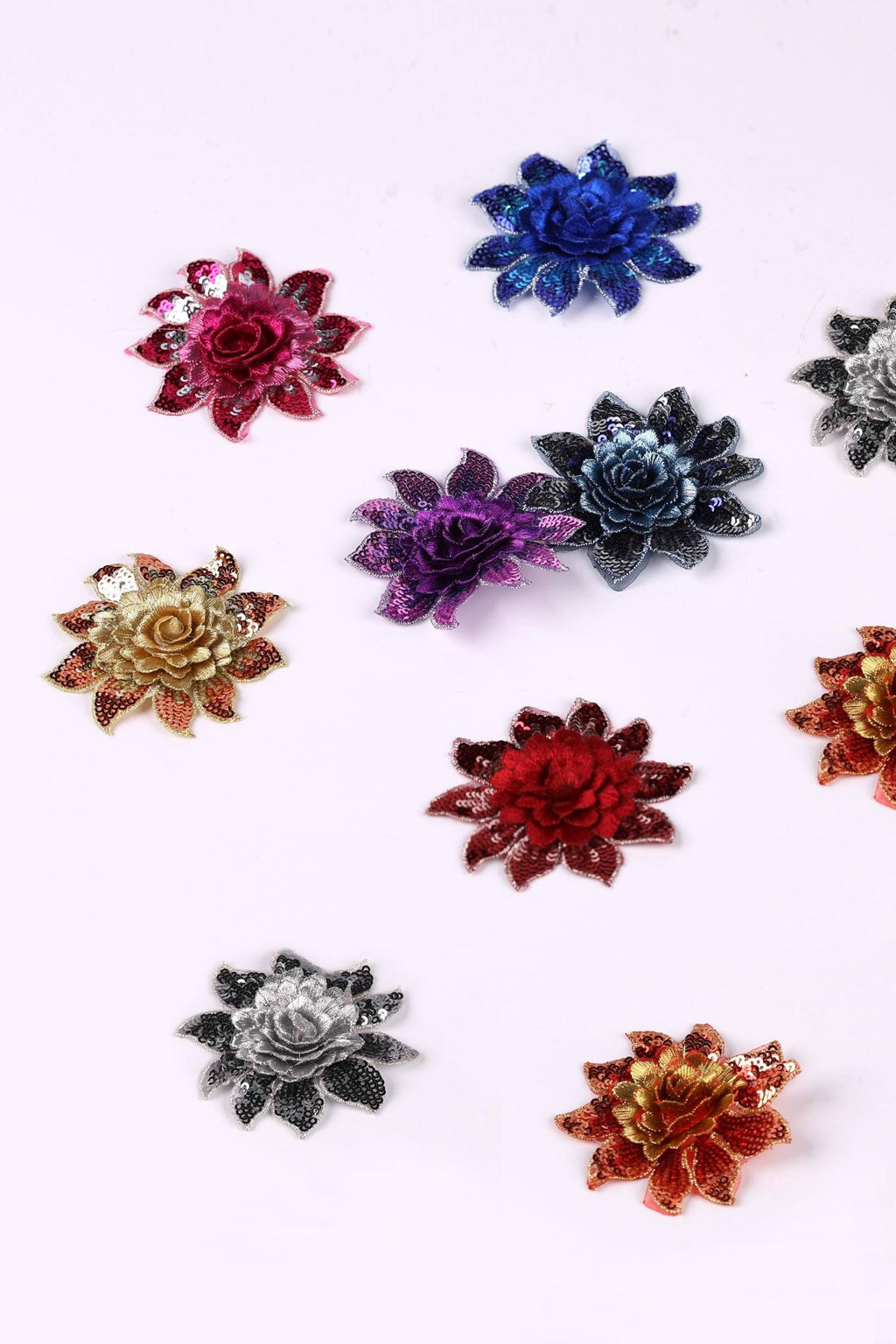 a collection of colorful, metallic flower-shaped embellishments arranged on a white background.