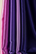 a close-up view of a collection of fabric swatches in various shades of purple and pink.