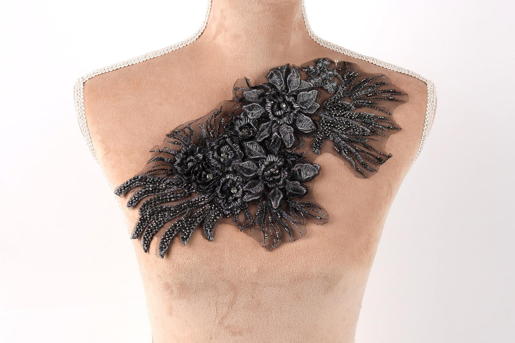 A mannequin torso with a decorative black lace or fabric piece featuring a floral pattern on the chest area.