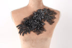 A mannequin torso with a decorative black lace or fabric piece featuring a floral pattern on the chest area.