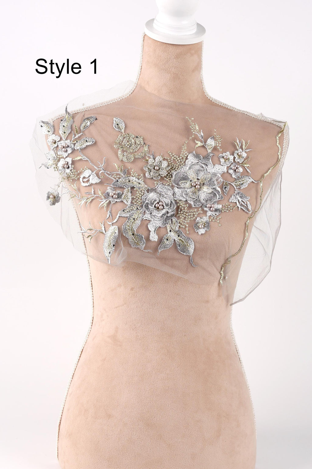 A mannequin wearing a sheer, floral-patterned fabric with a delicate, intricate design.