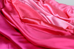 The image is a close-up of a fabric with a pink and red gradient, featuring a soft and flowing texture.