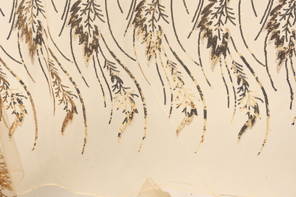 a close-up view of a fabric with a repeating pattern of gold and black sequin designs. The pattern consists of various shapes and lines, creating a visually striking and intricate design.