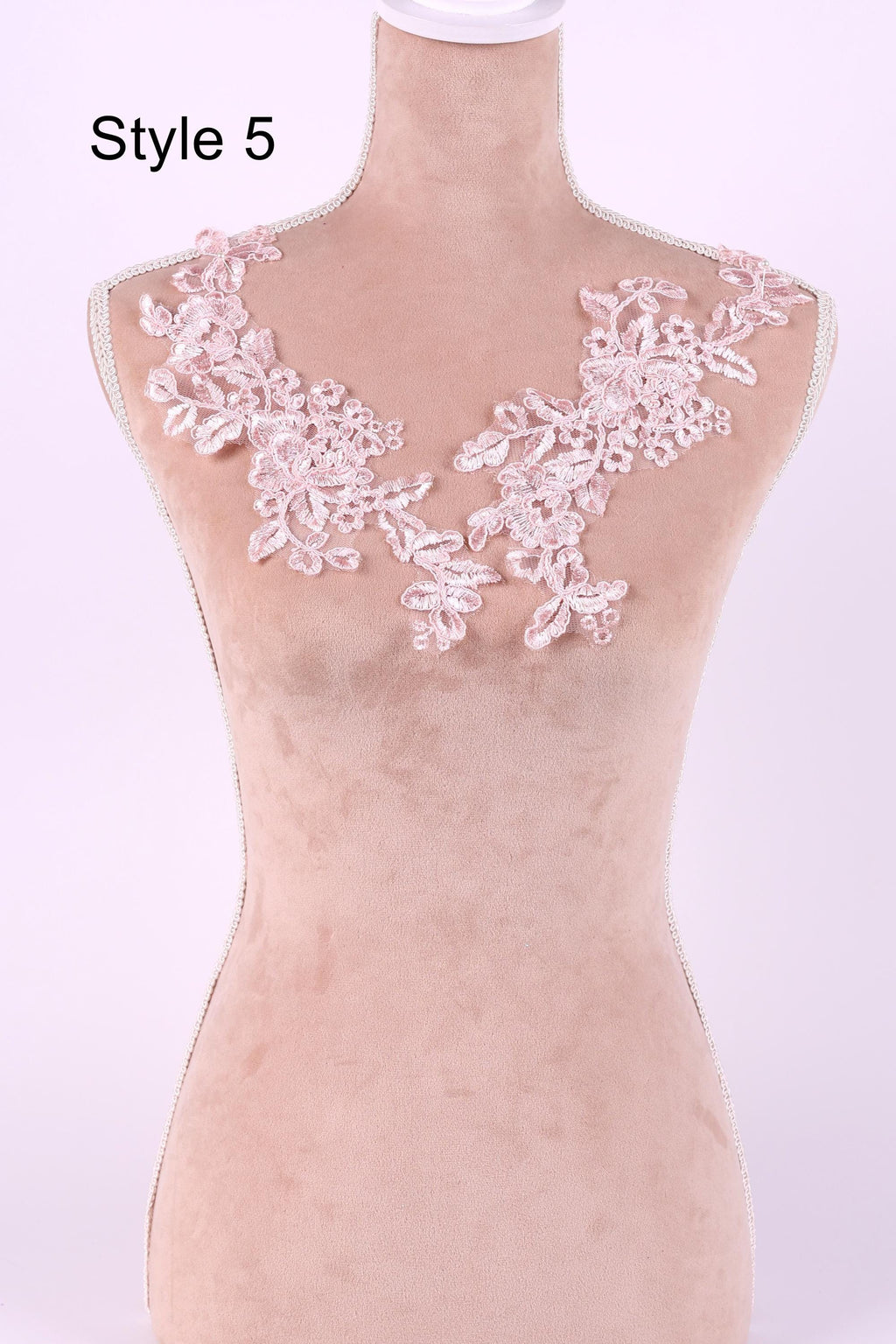 A mannequin wearing a pink lace collar with delicate floral patterns.