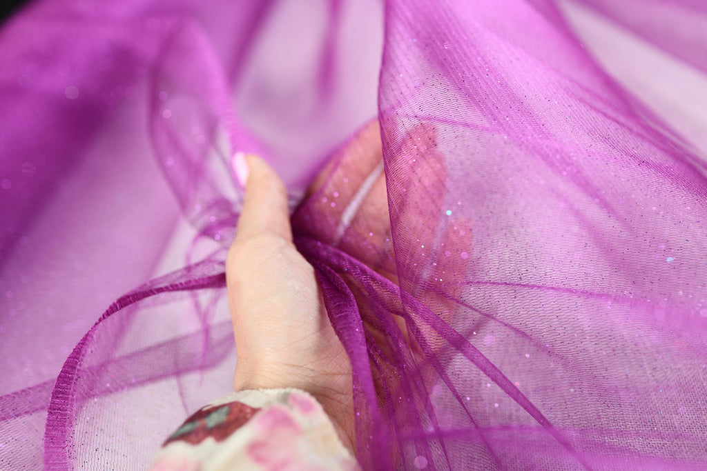 a woman's hand is holding a purple piece of fabric